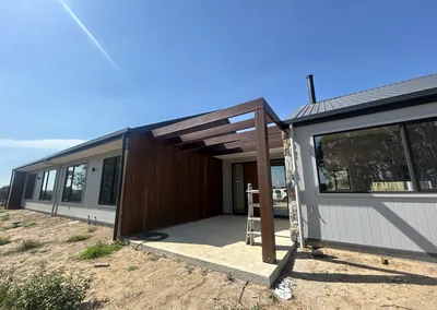 Timber-clad home with a timber pergola over the outdoor area