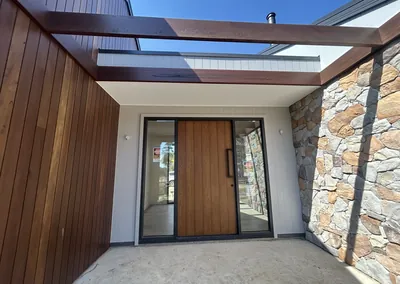 Timber pergola beams and timber cladding at a home entry