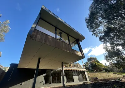 Timber-clad upper storey cantilevered over a sloping block